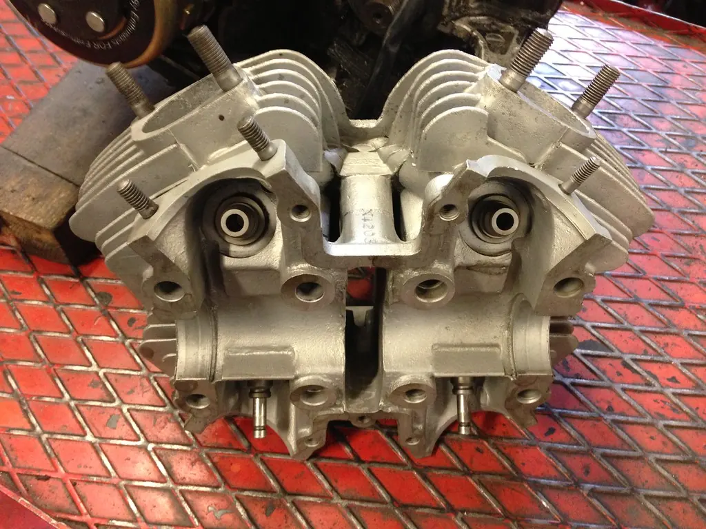 A machined motorcycle cylinder head on a workbench during an engine rebuild
