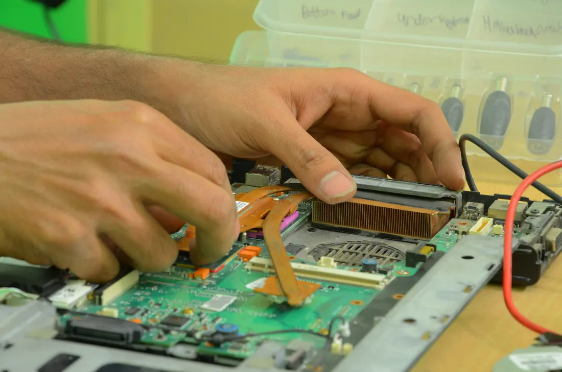 A technician's hands working on the inside of an open laptop